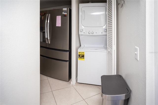 laundry room with light tile patterned flooring and stacked washer / dryer