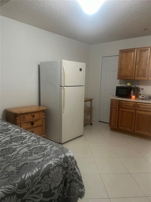 tiled bedroom with white refrigerator and a textured ceiling