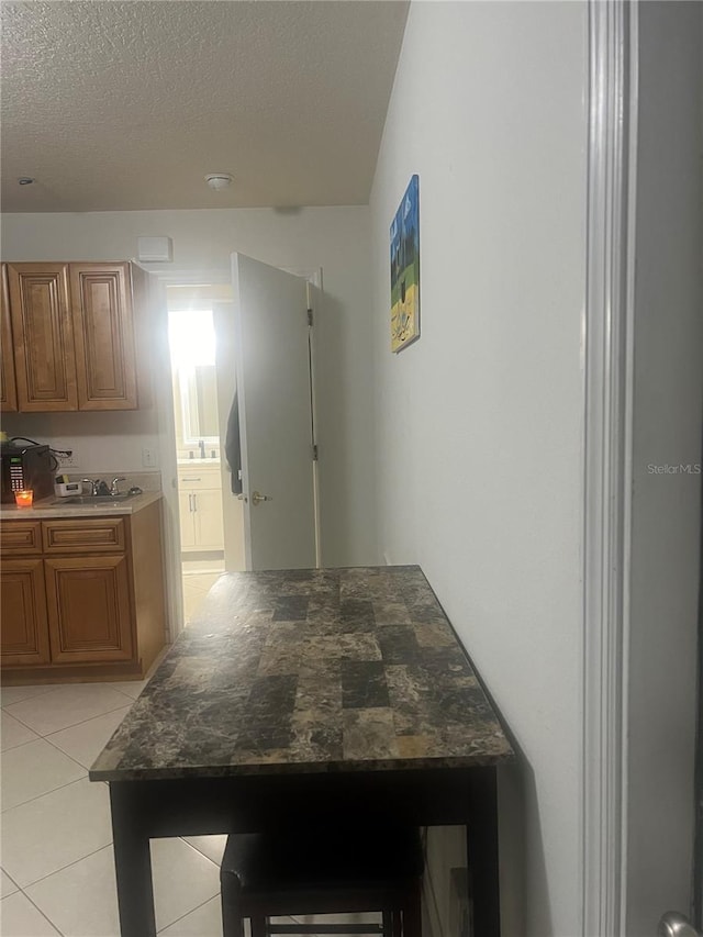 kitchen featuring light tile patterned flooring, sink, and a textured ceiling