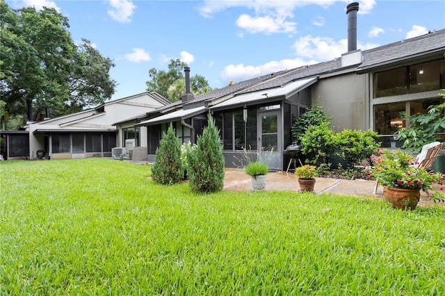 rear view of house featuring a sunroom and a lawn