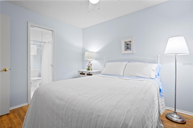 bedroom with ensuite bathroom, a textured ceiling, and hardwood / wood-style floors