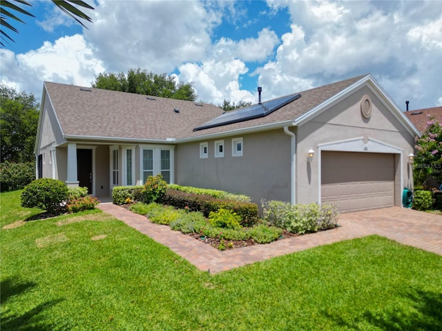 single story home with a garage, a front lawn, and solar panels