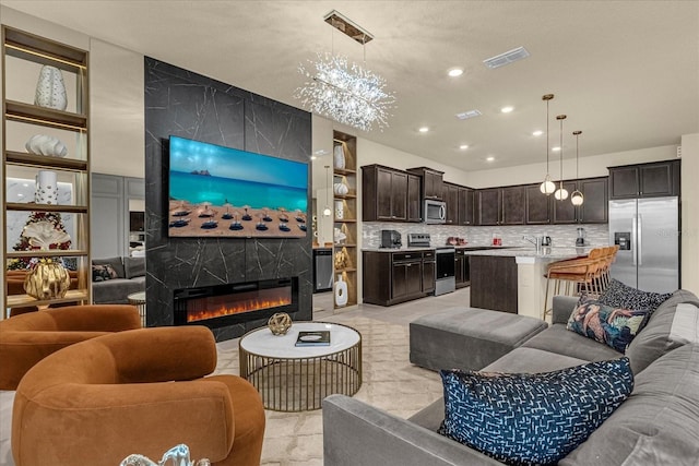 living room featuring a large fireplace, an inviting chandelier, and light tile patterned floors