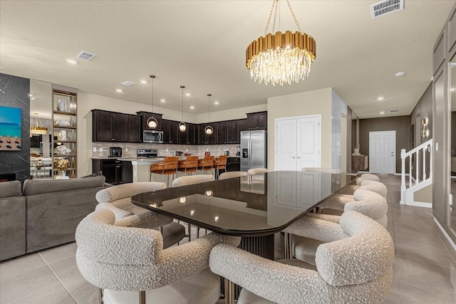 tiled dining space with a textured ceiling and an inviting chandelier