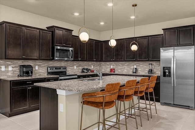 kitchen featuring stainless steel appliances, tasteful backsplash, a center island with sink, and pendant lighting