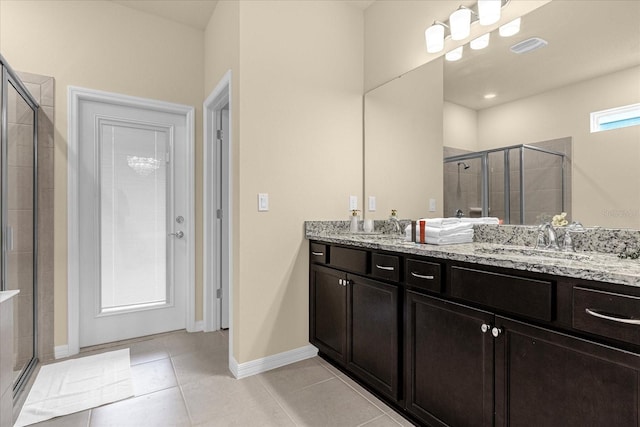 bathroom featuring a shower with door, double vanity, and tile patterned floors