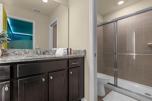 bathroom with vanity, a shower with shower door, toilet, and tile patterned floors