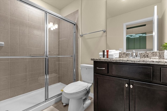 bathroom featuring tile patterned flooring, a shower with shower door, toilet, and vanity