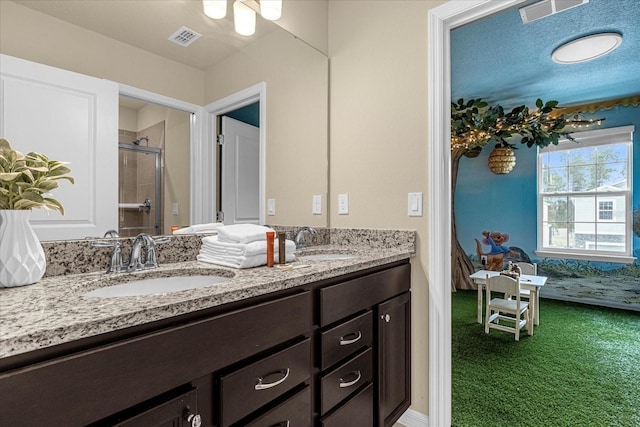 bathroom with a shower with shower door, a textured ceiling, and double vanity