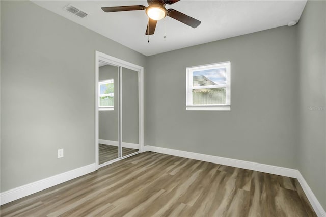 unfurnished bedroom with multiple windows, light hardwood / wood-style flooring, a closet, and ceiling fan