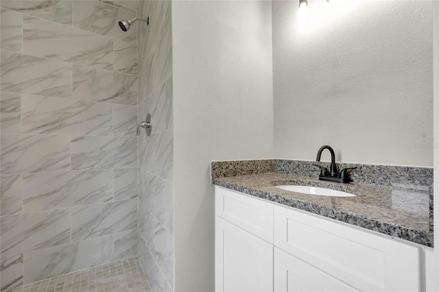 bathroom with vanity and tiled shower