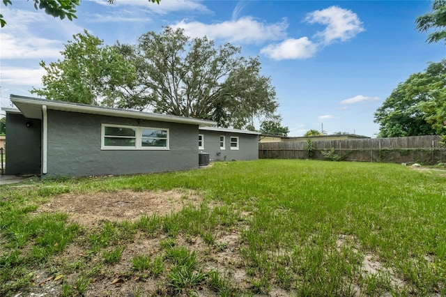 rear view of property with cooling unit and a lawn