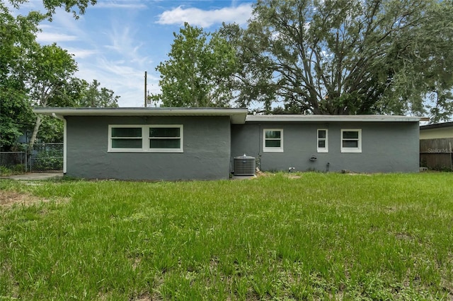 back of property featuring central AC unit and a yard