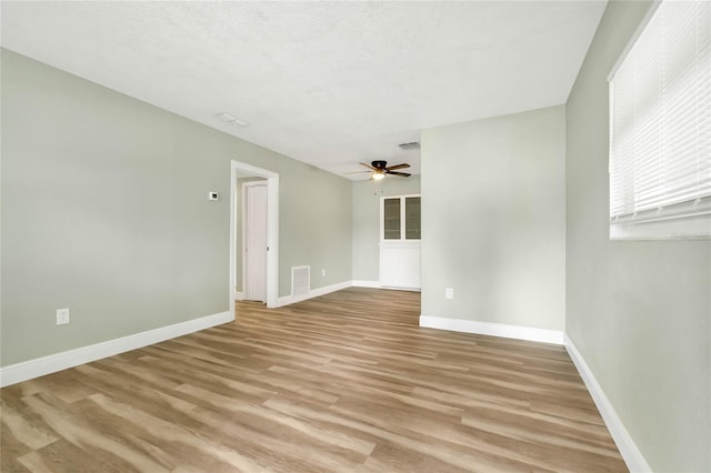 empty room featuring a textured ceiling, ceiling fan, and light wood-type flooring