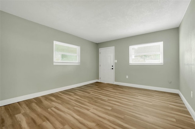 unfurnished room with a textured ceiling and light hardwood / wood-style floors