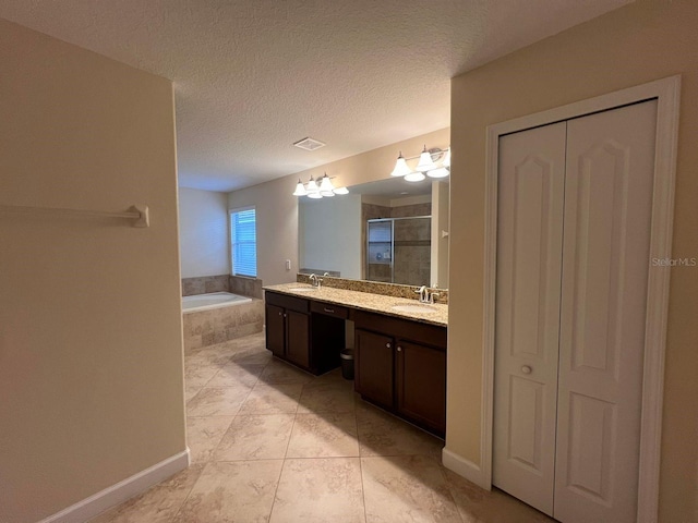 bathroom with plus walk in shower, a textured ceiling, tile patterned floors, and vanity