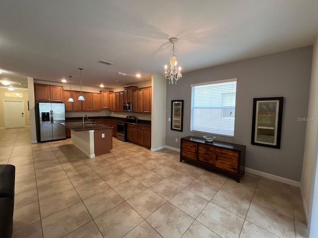 kitchen featuring appliances with stainless steel finishes, sink, pendant lighting, and a center island with sink