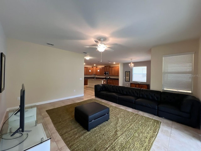 living room with sink, light tile patterned flooring, and ceiling fan with notable chandelier