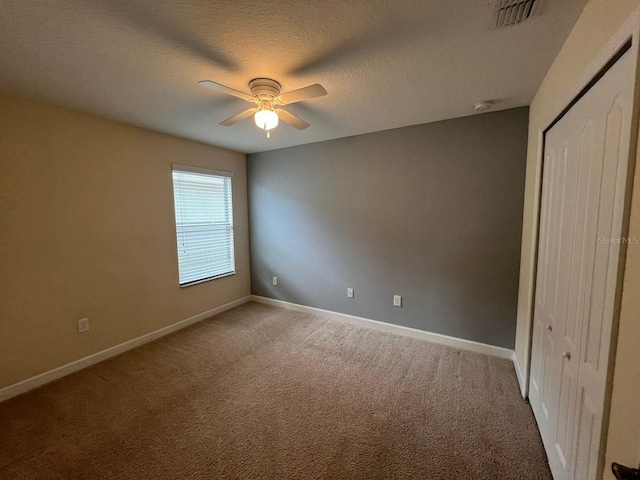 unfurnished bedroom featuring ceiling fan, carpet, a closet, and a textured ceiling