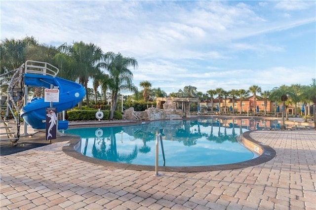 view of pool with a water slide and a patio