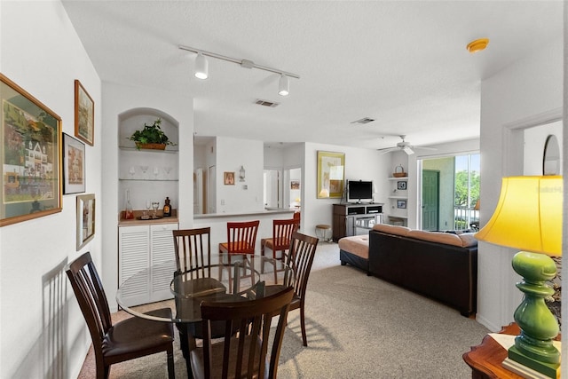 carpeted dining space featuring track lighting, ceiling fan, and a textured ceiling