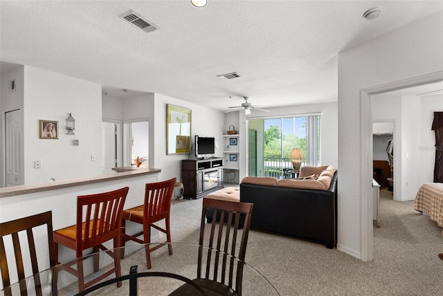 dining room with light carpet, a textured ceiling, and ceiling fan