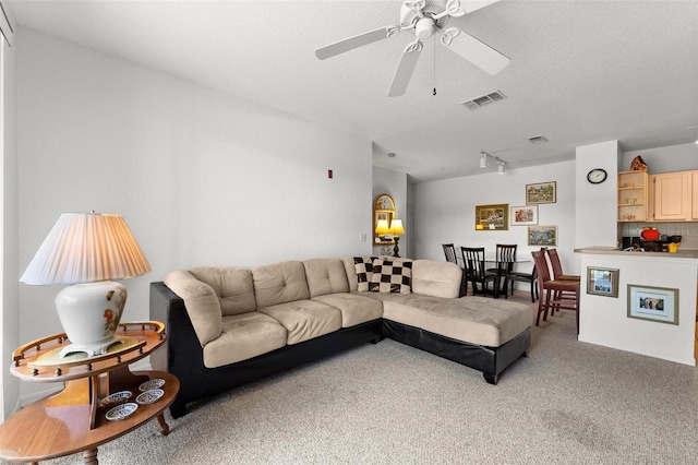 living room featuring track lighting, ceiling fan, carpet, and a textured ceiling