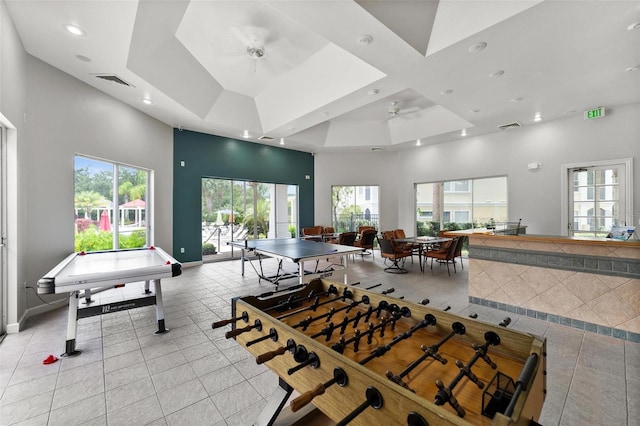 game room featuring light tile patterned floors, a raised ceiling, a high ceiling, and ceiling fan