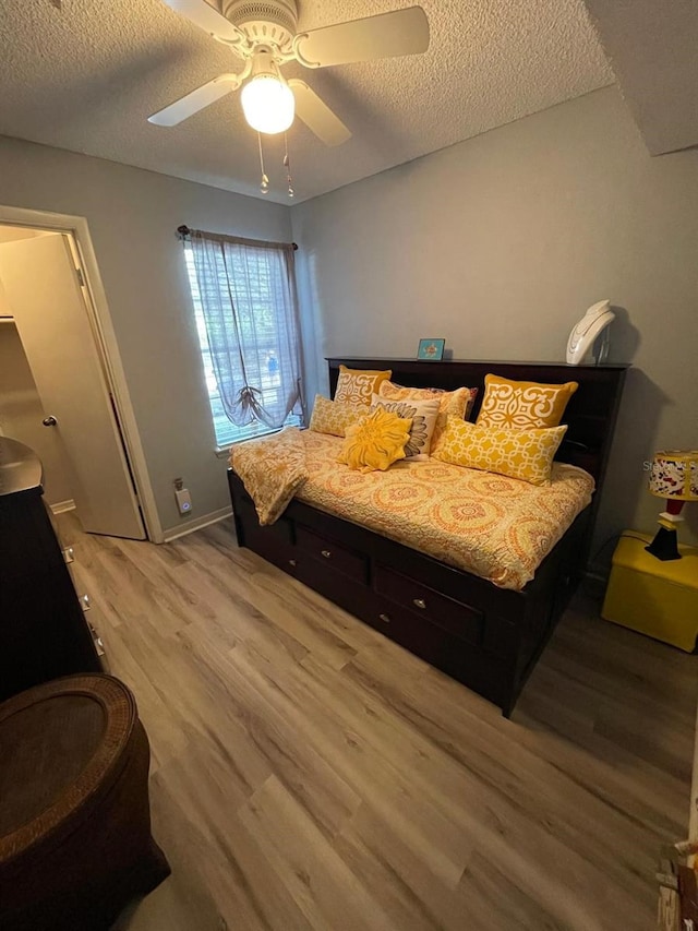 bedroom with light wood-type flooring, ceiling fan, and a textured ceiling