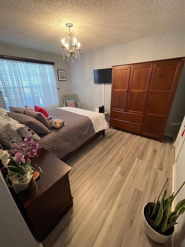 bedroom featuring an inviting chandelier, a textured ceiling, and light hardwood / wood-style floors