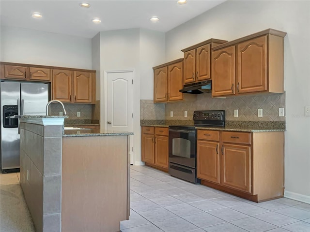 kitchen featuring stone counters, stainless steel fridge with ice dispenser, black electric range, an island with sink, and light tile patterned flooring