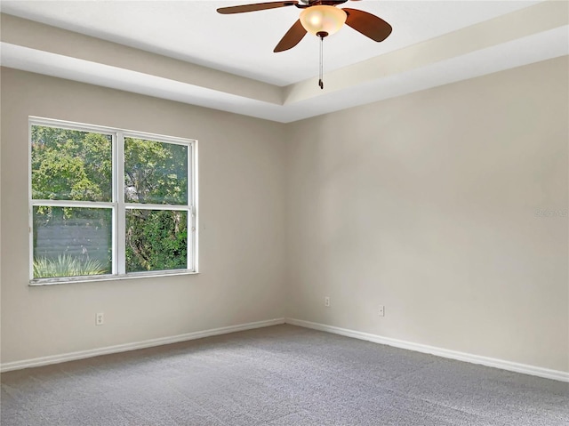 spare room featuring carpet, ceiling fan, and a raised ceiling