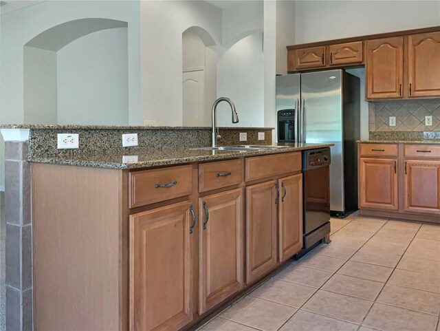 kitchen featuring stone counters, sink, light tile patterned flooring, and appliances with stainless steel finishes