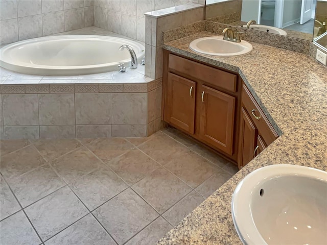 bathroom featuring tile patterned flooring, vanity, and tiled bath