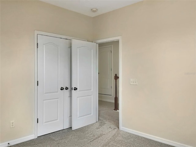 unfurnished bedroom with light colored carpet and a closet