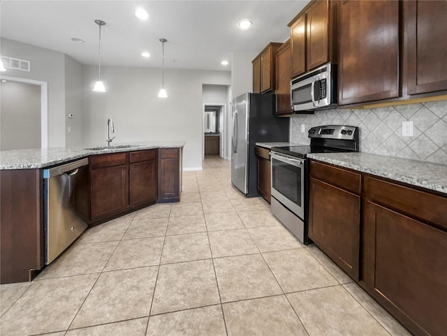 kitchen featuring sink, decorative light fixtures, light tile patterned flooring, light stone counters, and stainless steel appliances