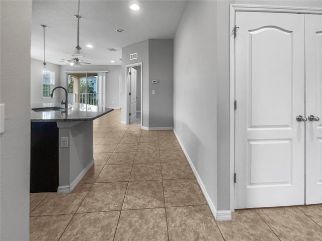 kitchen featuring tile patterned floors, sink, ceiling fan, kitchen peninsula, and a breakfast bar area