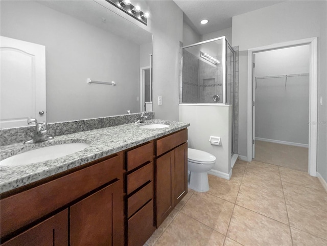 bathroom featuring tile patterned floors, vanity, toilet, and a shower with door