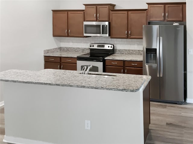 kitchen featuring stainless steel appliances, backsplash, light wood-type flooring, and a sink