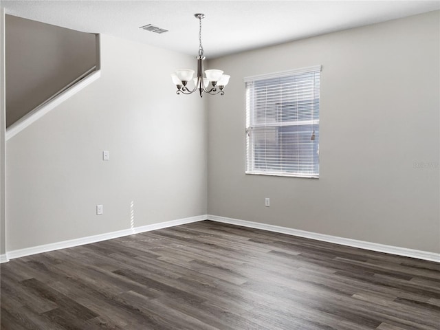 unfurnished dining area featuring dark wood-type flooring, a chandelier, visible vents, and baseboards