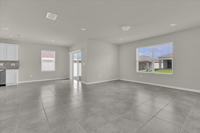 unfurnished living room with light tile patterned flooring and a wealth of natural light