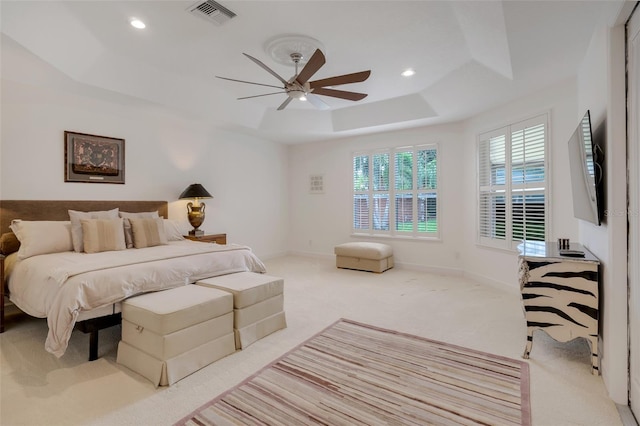 carpeted bedroom featuring ceiling fan and a tray ceiling