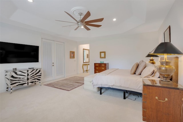 carpeted bedroom featuring ceiling fan and a tray ceiling