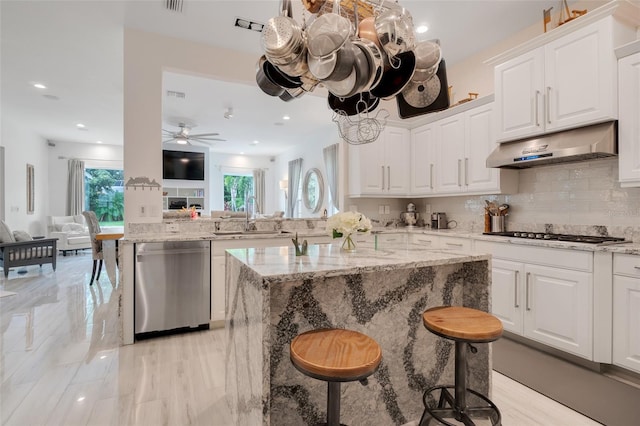 kitchen with white cabinetry, ceiling fan, stainless steel appliances, a kitchen breakfast bar, and sink