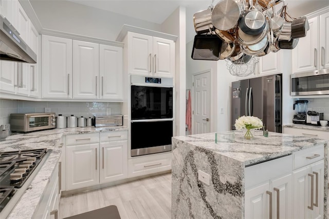 kitchen featuring white cabinetry, backsplash, stainless steel appliances, light hardwood / wood-style floors, and wall chimney exhaust hood