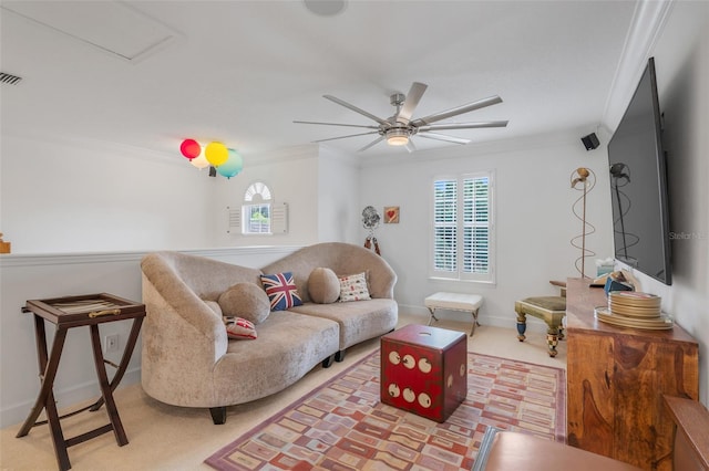 carpeted living room with crown molding and ceiling fan