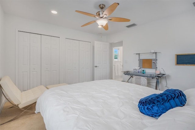 bedroom featuring multiple closets, light carpet, and ceiling fan