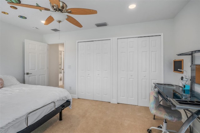 bedroom with multiple closets, light carpet, and ceiling fan