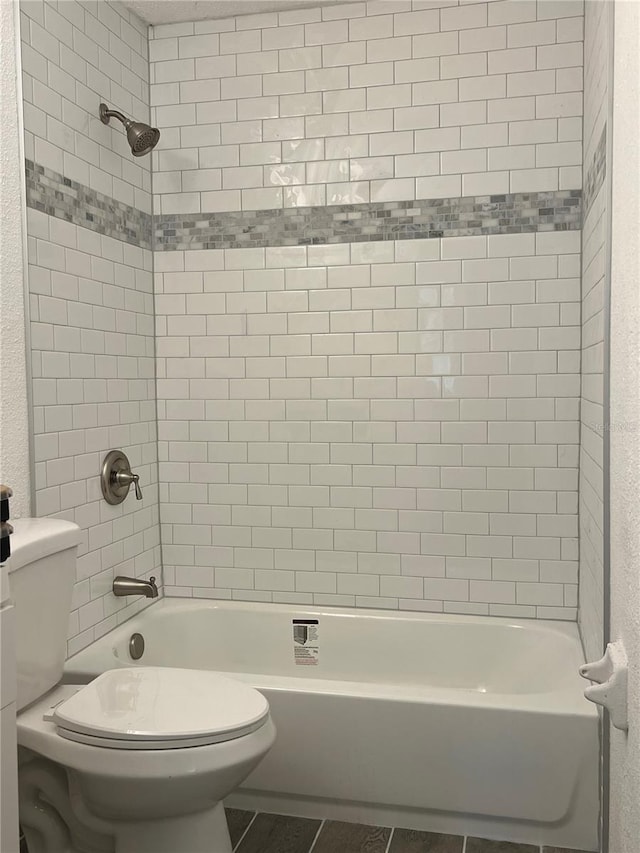 bathroom with tile patterned floors, tiled shower / bath combo, and toilet