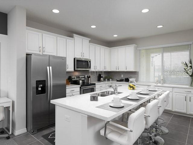 kitchen featuring stainless steel appliances, a breakfast bar, sink, and white cabinets